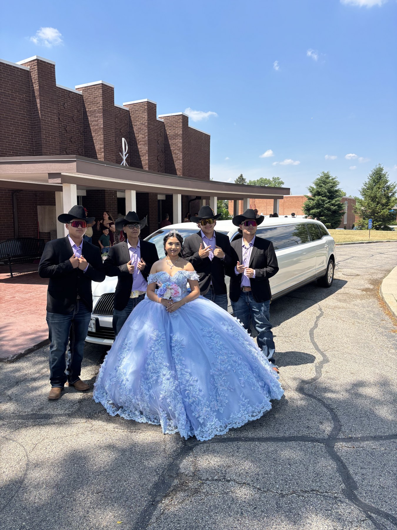 Quinceañera celebration group beside a white stretch limousine.